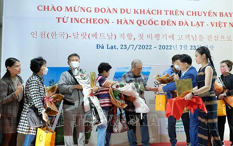 Đại diện Sở Văn hóa, Thể thao và Du lịch Lâm Đồng tặng hoa chúc mừng những du khách quốc tế đầu tiên đến Đà Lạt hôm 23/7. (Ảnh: TTXVN) 