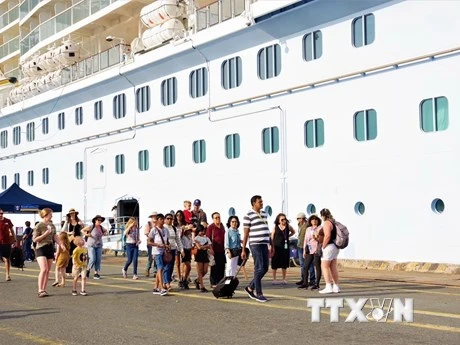 Du khách trên tàu Spectrum of the Seas di chuyển trên cầu cảng trước khi lên xe tham quan. (Ảnh: TTXVN)