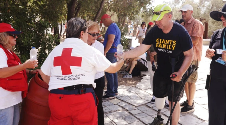 Một tình nguyện viên của dịch vụ y tế khẩn cấp tại Hy Lạp phát nước miễn phí cho du khách tại thành cổ Acropolis hôm 14/7. (Ảnh: REUTERS) 