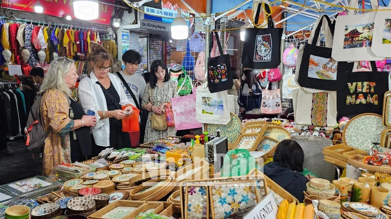 Du khách nước ngoài thích thú mua đồ lưu niệm đậm chất Việt Nam tại chợ đêm phố cổ, Hà Nội, tháng 1/2024. (Ảnh: T.LINH)