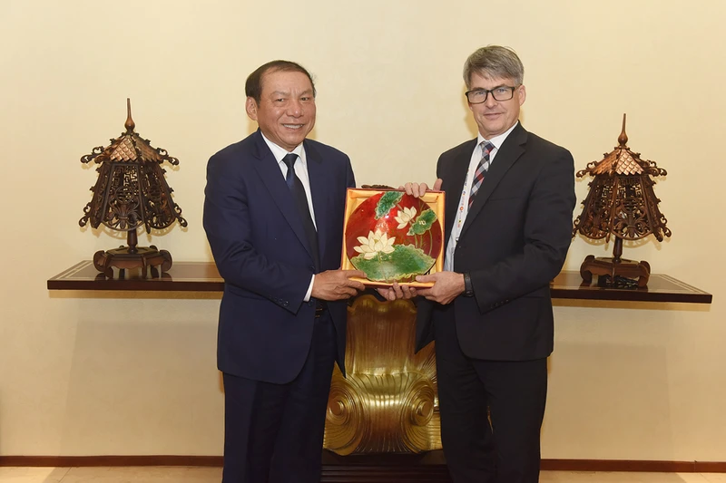 Bộ trưởng Nguyễn Văn Hùng tặng quà lưu niệm Nguyên Đại sứ Brian McFeeters. (Ảnh: Cục Du lịch Quốc gia Việt Nam) 
