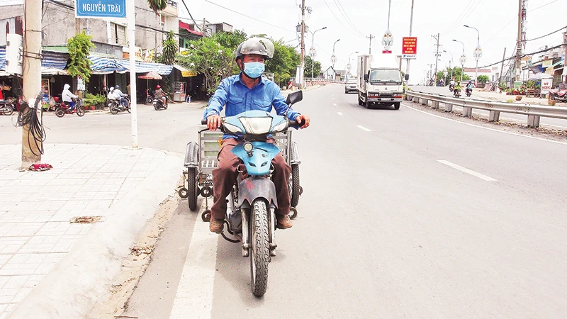 Ông Út lái xe tự chế hút đinh trên Quốc lộ 91, tỉnh An Giang.