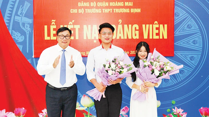 Đồng chí Nguyễn Quang Hiếu, Bí thư Quận ủy, Chủ tịch HĐND quận Hoàng Mai tặng hoa chúc mừng hai học sinh Trường THPT Trương Định được kết nạp vào đảng.