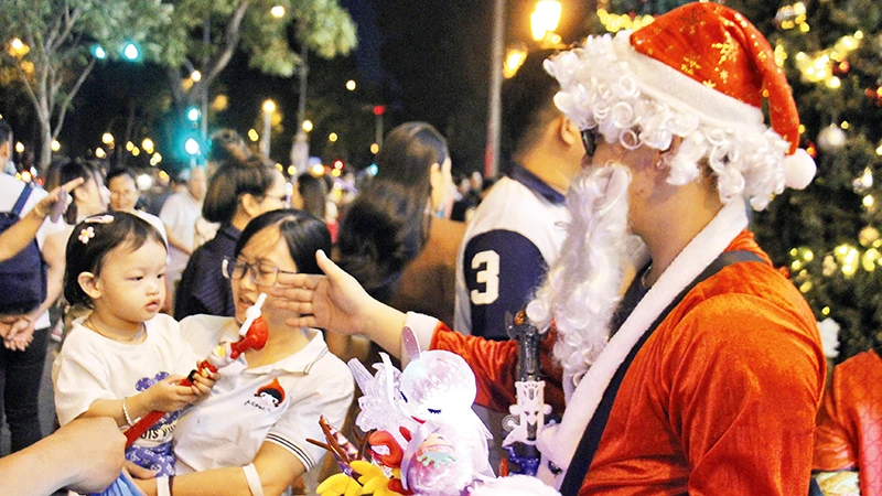 Ông già Noel phát quà cho các trẻ em tại khu vực trang trí giáng sinh tại trung tâm thành phố (Ảnh THẾ ANH)