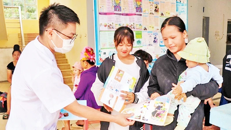 Cán bộ Trạm Y tế xã Mường Cai, huyện Sông Mã, tỉnh Sơn La phát tờ rơi tuyên truyền về công tác dân số cho nhân dân. (Ảnh HUYỀN TRANG)