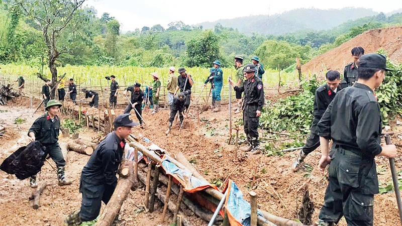 Các chiến sĩ Công an tỉnh Bắc Kạn giúp người dân xã Quang Thuận, huyện Bạch Thông khắc phục hậu quả sạt, lở đất. (Ảnh THÙY DƯƠNG)