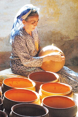 Nghệ nhân Ưu tú Đơn Thị Hiệu, làng gốm Chăm Bình Đức đang tạo hình một sản phẩm gốm. (Ảnh: Ngọc Lân)