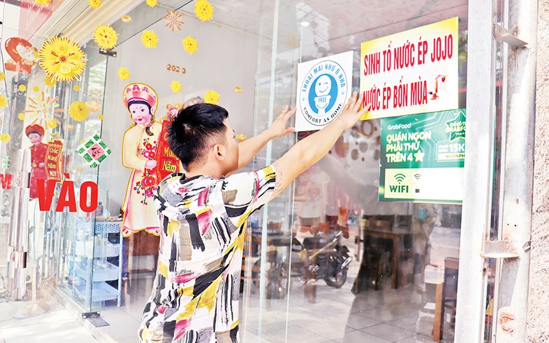 Nhân viên một cơ sở du lịch ở Đà Nẵng dán biểu tượng xã hội hóa nhà vệ sinh công cộng tại khu vực dễ thấy. (Ảnh Thanh Tâm)