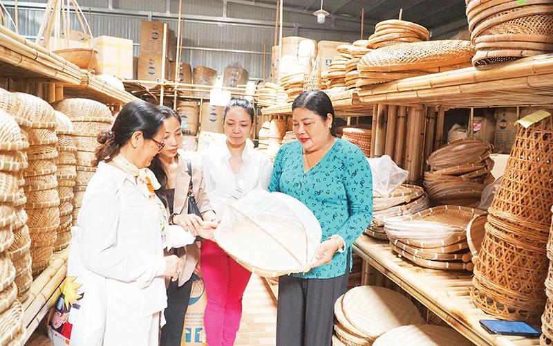 Nghệ nhân Trương Thị Bạch Thủy (bên phải) giới thiệu với du khách tham quan tại phòng trưng bày sản phẩm của Hợp tác xã Mây tre đan Thủy Tuyết.