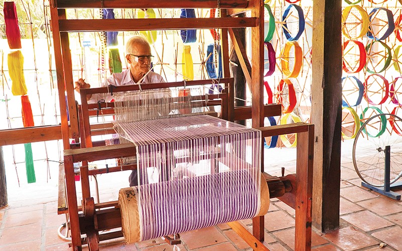 Ông Bảy Nghề trình diễn dệt khăn choàng bằng tay tại Long Khương Miếu, di tích lịch sử cấp tỉnh ở Đồng Tháp.