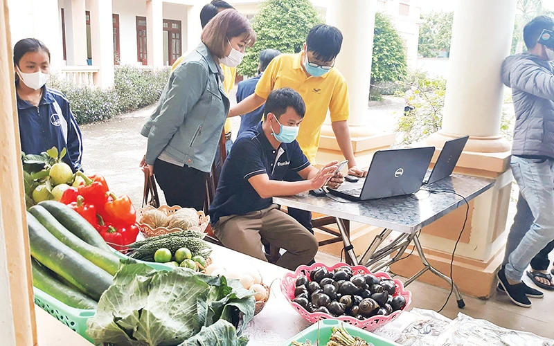 Hướng dẫn người dân xã Yên Hòa, huyện Yên Mô cài đặt phần mềm để đưa sản phẩm lên sàn giao dịch thương mại điện tử. (Ảnh Nguyễn Trường)