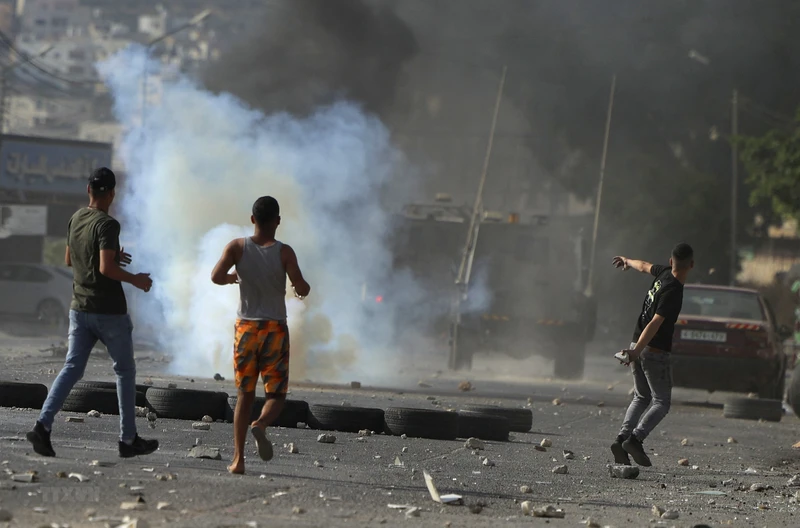 Người biểu tình Palestine ném đá trong cuộc xung đột với binh sỹ Israel tại thành phố Nablus, Khu Bờ Tây ngày 17/8/2022. (Ảnh minh họa: AFP/TTXVN)