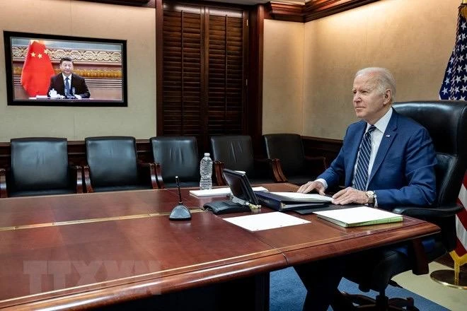 Tổng thống Mỹ Joe Biden và Chủ tịch Trung Quốc Tập Cận Bình (trên màn hình) tại cuộc họp trực tuyến ngày 18/3/2022. (Ảnh: AFP/TTXVN)