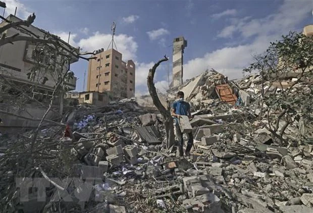 Người dân Palestine tìm kiếm đồ đạc còn sót lại trong toà nhà đã bị phá hủy trong các cuộc không kích của máy bay Israel xuống Dải Gaza. (Ảnh: AFP/TTXVN)
