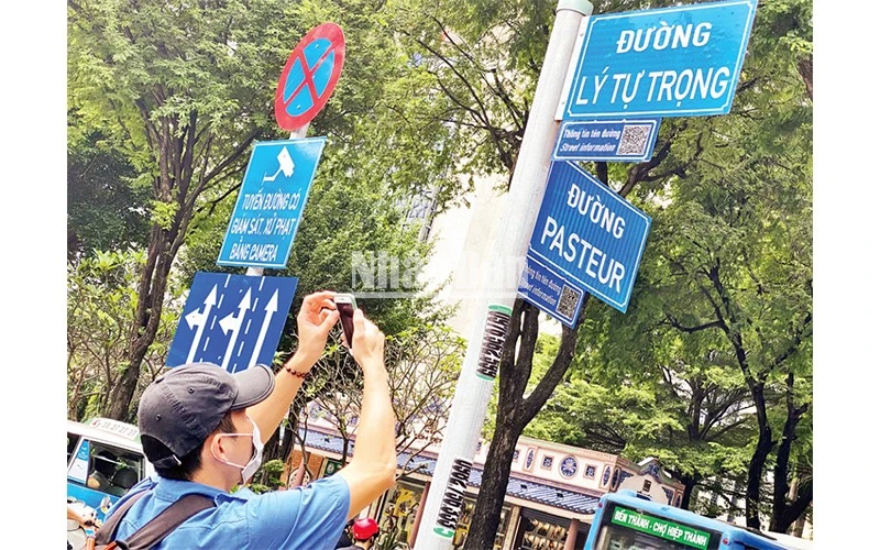 Một du khách tra cứu thông tin tên đường từ mã QR gắn ở giao lộ Lý Tự Trọng-Pasteur, quận 1, TP Hồ Chí Minh.
