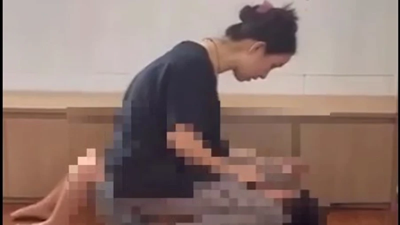 Người phụ nữ ngồi lên bụng cháu bé mặc cho bé khóc thét, sợ hãi (Ảnh cắt từ clip)