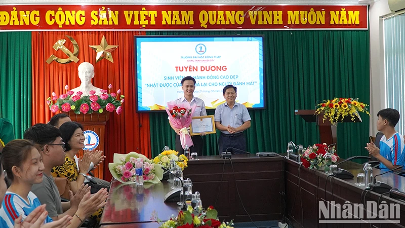 Đại diện lãnh đạo Trường Đại học Đồng Tháp Cao Dao Thép trao giấy khen và tiền thưởng cho em Nguyễn Minh Toàn. (Ảnh: HỮU NGHĨA)