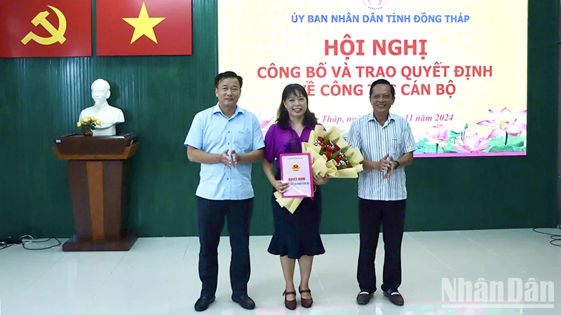 Phó Chủ tịch Ủy ban nhân dân tỉnh Đồng Tháp Nguyễn Phước Thiện (bìa trái) trao quyết định, Giám đốc Sở Nội vụ Phan Hữu Phước tặng hoa chúc mừng nhà báo Ngô Thị Ngọc Hạnh.