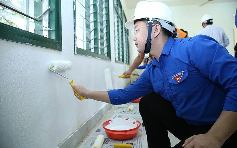 Tình nguyện viên sơn, sửa các mảng rêu mốc trên tường lớp học trong khuôn khổ lễ ra quân chương trình “Trường em thay áo mới”.