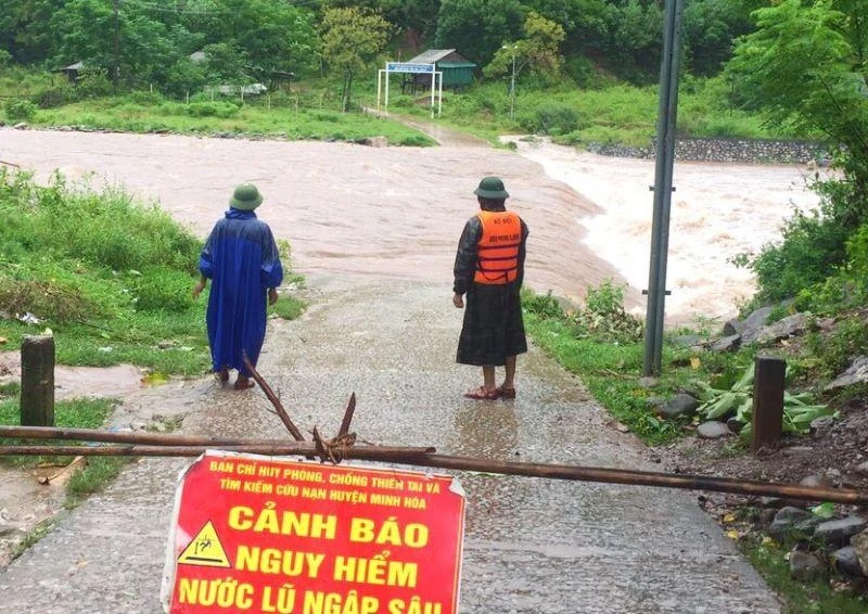 Lực lượng chức năng đặt biển cảnh báo và cử tổ công tác cảnh giới đoạn đường ngập sâu ở huyện Minh Hóa.