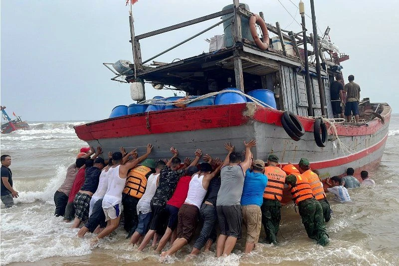 Các lực lượng chức năng và người dân tham gia cứu hộ tàu cá TTH-923.49 TS bị mắc cạn ở bờ biển thôn Cự Lại Nam, xã Phú Hải, huyện Phú Vang.