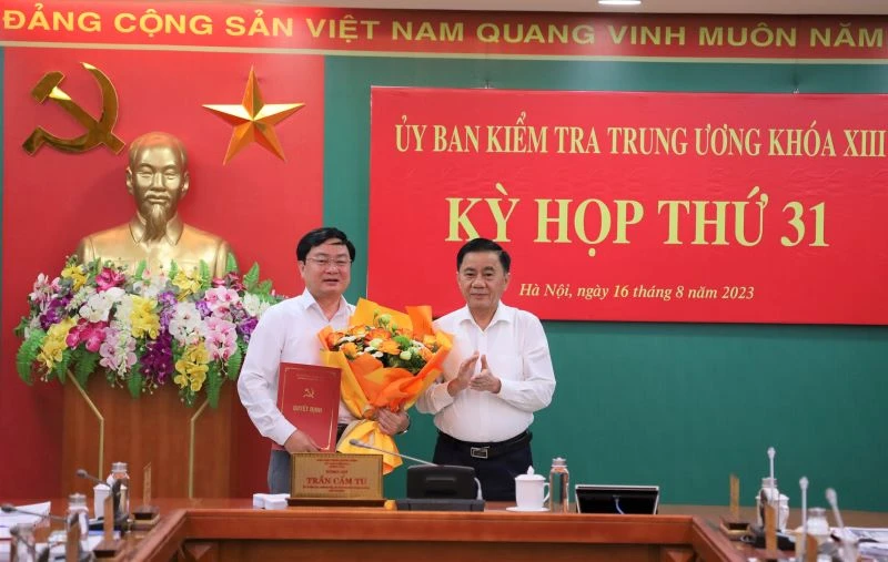 Đồng chí Trần Cẩm Tú, Ủy viên Bộ Chính trị, Bí thư Trung ương Đảng, Chủ nhiệm Ủy ban kiểm tra Trung ương trao quyết định và tặng hoa chúc mừng đồng chí Nguyễn Văn Quyết.