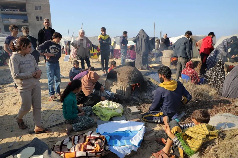 Người dân chuẩn bị bữa ăn tại trại tạm dành cho người tị nạn ở Rafah, miền Nam Dải Gaza ngày 18/12/2023. (Ảnh: THX/TTXVN)