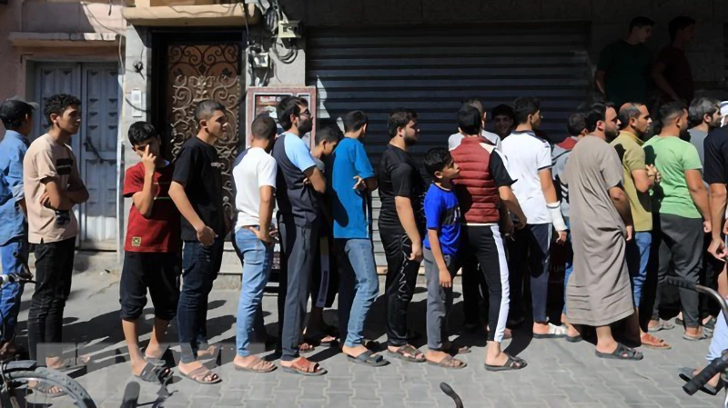Người dân xếp hàng chờ mua thực phẩm tại miền nam Dải Gaza. (Ảnh: THX/TTXVN)