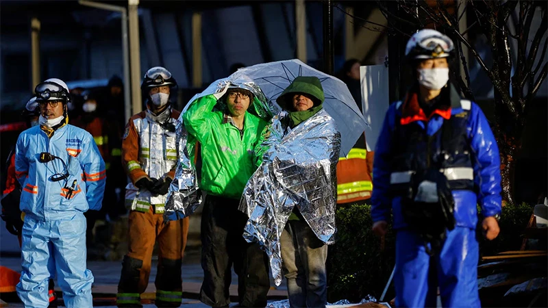 Người dân choàng chăn bạc giữ nhiệt theo dõi hoạt động cứu nạn tại thành phố Wajima, tỉnh Ishikawa, Nhật Bản, ngày 3/1/2024. (Ảnh: REUTERS)
