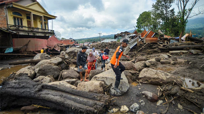 Người dân địa phương đi qua khu vực chịu ảnh hưởng của mưa lớn. (Ảnh: Reuters)