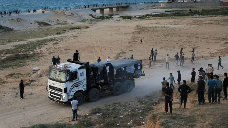 Xe tải chở hàng viện trợ qua bến tàu nổi do Mỹ thiết lập vào miền trung Dải Gaza, ngày 17/5/2024. (Ảnh: THX/TTXVN)