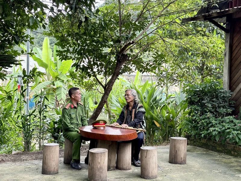 Trung tá Ating Chơn trao đổi với già làng Bríu Pố về công tác giữ gìn an ninh trật tự.