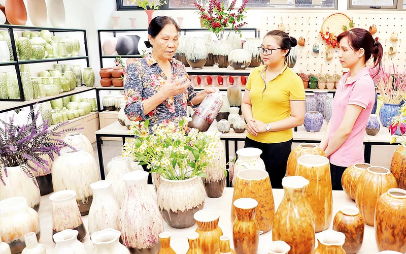Doanh nhân Hà Thị Vinh (ngoài cùng bên trái) hướng dẫn nhân viên quảng bá sản phẩm gốm sứ Quang Vinh.