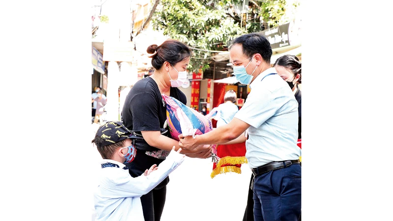 Lãnh đạo phường Dịch Vọng Hậu, quận Cầu Giấy trao quà hỗ trợ người dân có hoàn cảnh khó khăn trong đợt dịch Covid-19. (Ảnh DUY LINH)