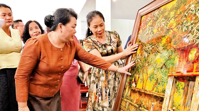 Nghệ nhân làng nghề sơn mài của Hà Nội giới thiệu sản phẩm tới Ðoàn công tác của Sở Công thương Viêng Chăn (Lào).