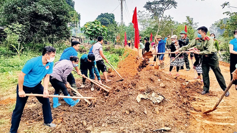 Cán bộ các cơ quan tỉnh Tuyên Quang tham gia san gạt, đắp lề đường cùng nhân dân thôn Mỏ Nghiều 2, xã Tân Thành, huyện Hàm Yên.