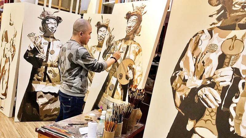 Họa sĩ Võ Thành Thân trong xưởng vẽ với bộ tranh lấy cảm hứng từ văn hóa truyền thống Huế. (Ảnh: NVCC)