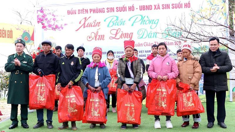 Ðại diện lãnh đạo Bộ đội Biên phòng tỉnh Lai Châu và huyện Phong Thổ trao quà tặng các hộ nghèo ở bản Chí Sáng, xã Sin Suối Hồ, huyện Phong Thổ. (Ảnh ÐỨC DUẨN)