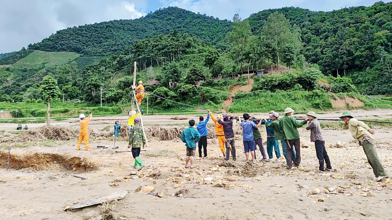 Công nhân Công ty Ðiện lực Sơn La kéo điện lên các bản bị ảnh hưởng mưa lũ của xã Chiềng Nơi, huyện Mai Sơn. (Ảnh LUYỆN NGỌC TUẤN)