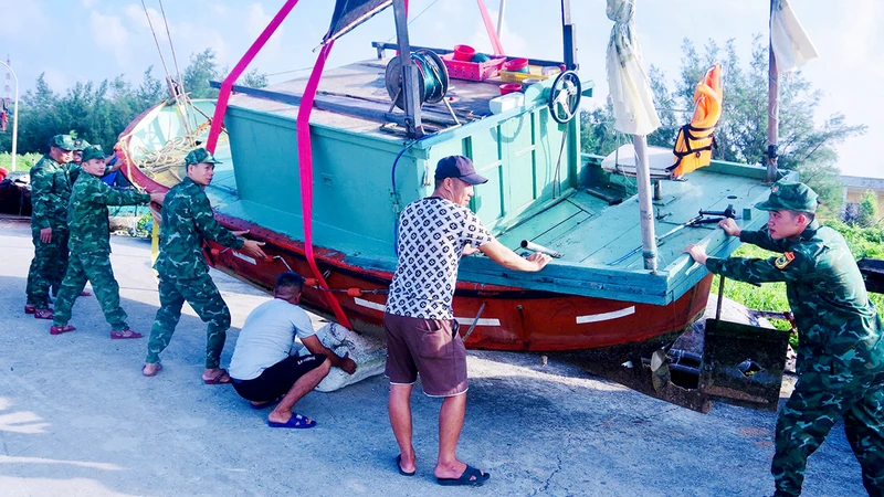 Lực lượng Biên phòng đảo Bạch Long Vĩ (Hải Phòng) hỗ trợ ngư dân di chuyển tàu thuyền lên bờ. (Ảnh SƠN HÀ)