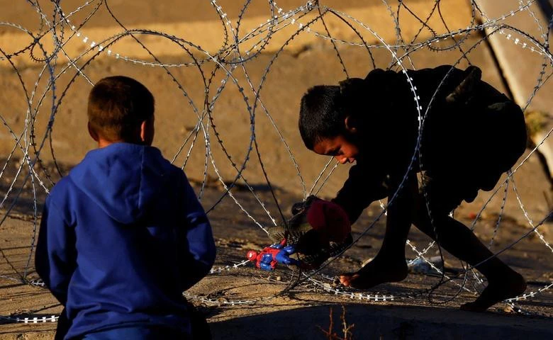  Một cậu bé di cư cố gắng vượt qua hàng rào thép gai do Lực lượng Vệ binh Quốc gia Texas đặt tại biên giới giữa Hoa Kỳ và Mexico với mục đích củng cố an ninh biên giới và ngăn chặn người di cư vượt biên vào Hoa Kỳ, ngày 7/1/2023. (Ảnh: REUTERS)