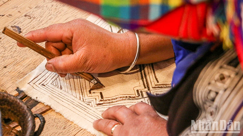 Nghệ nhân người H’Mông vẽ sáp ong trên vải lanh.(Ảnh: Hà Nam)