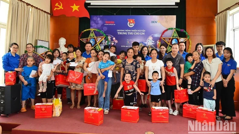 Đoàn viên, thanh niên Báo Nhân Dân, Chi đoàn Ban Kiểm tra và Giám sát tuân thủ (Ngân hàng BIDV) tặng quà các em nhỏ của Làng Hòa Bình Thanh Xuân, Hà Nội. (Ảnh: THỦY NGUYÊN)