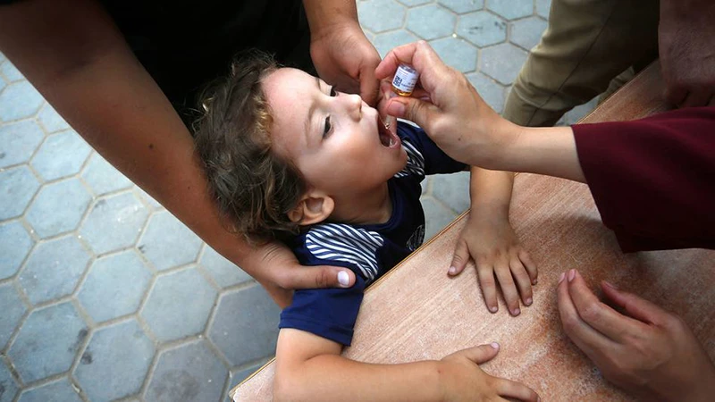 Một nhân viên y tế cho trẻ em Palestine uống vaccine bại liệt ở Deir Al-Balah, miền trung Gaza. (Ảnh UNRWA)