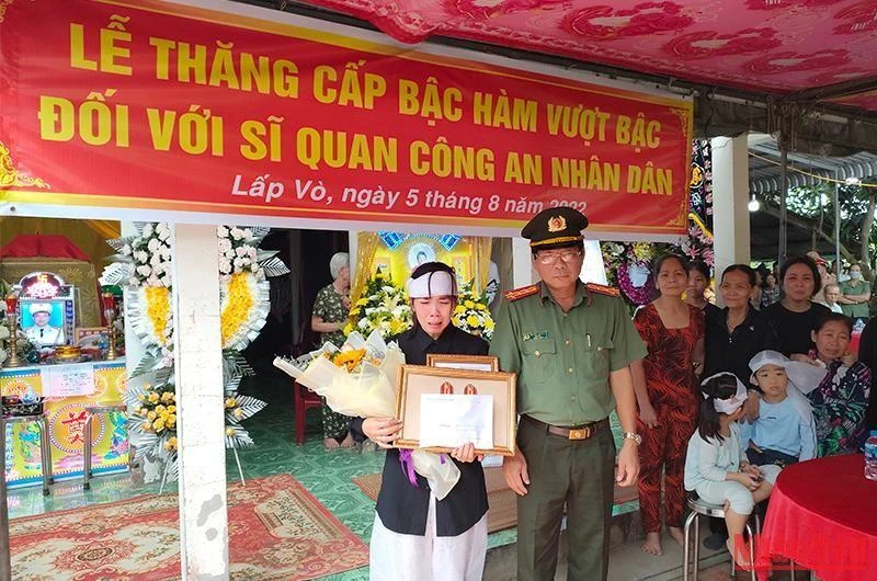 Đại tá Nguyễn Văn Hiểu - Giám đốc Công an tỉnh Đồng Tháp trao quyết định thăng cấp bậc hàm cho đồng chí Dương, vợ đồng chí Dương nhận. (Ảnh: HỮU NGHĨA)