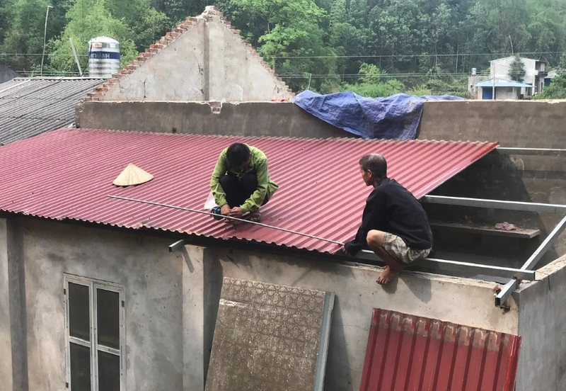Người dân huyện Bạch Thông lợp lại mái nhà bị tốc do mưa lốc. (Ảnh: HƯƠNG DỊU)