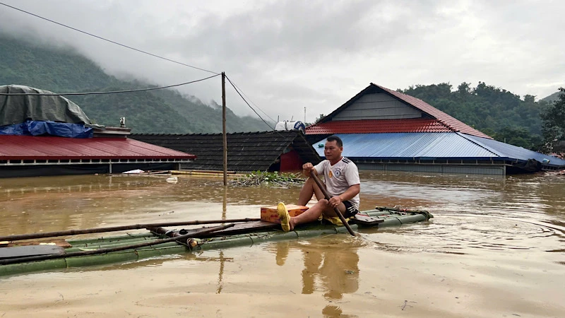 Một hộ dân ở xã Nam Cường, huyện Chợ Đồn di chuyển qua nước ngập bằng bè tre đi nhận nhu yếu phẩm hỗ trợ. (Ảnh: ĐÌNH HỢI).