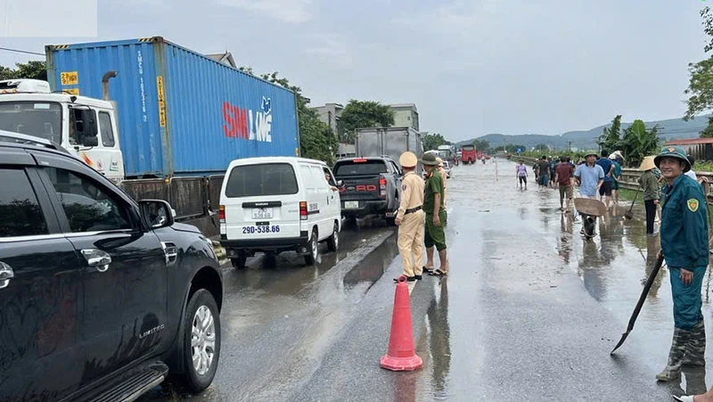 Lực lượng chức năng điều tiết, hướng dẫn giao thông tại điểm Quốc lộ 1A ở huyện Hà Trung (Thanh Hóa) bị ngập nước.