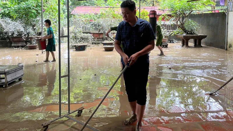 Hộ gia đình chủ động gạt bùn, làm vệ sinh nhà ở sau ngập nước.