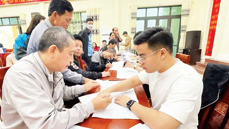 Cán bộ Trung tâm Phát triển quỹ đất huyện Thường Tín hướng dẫn người dân xã Văn Bình hoàn thiện thủ tục nhận tiền giải phóng mặt bằng dự án đường vành đai 4. (Ảnh: CÔNG TÂM)